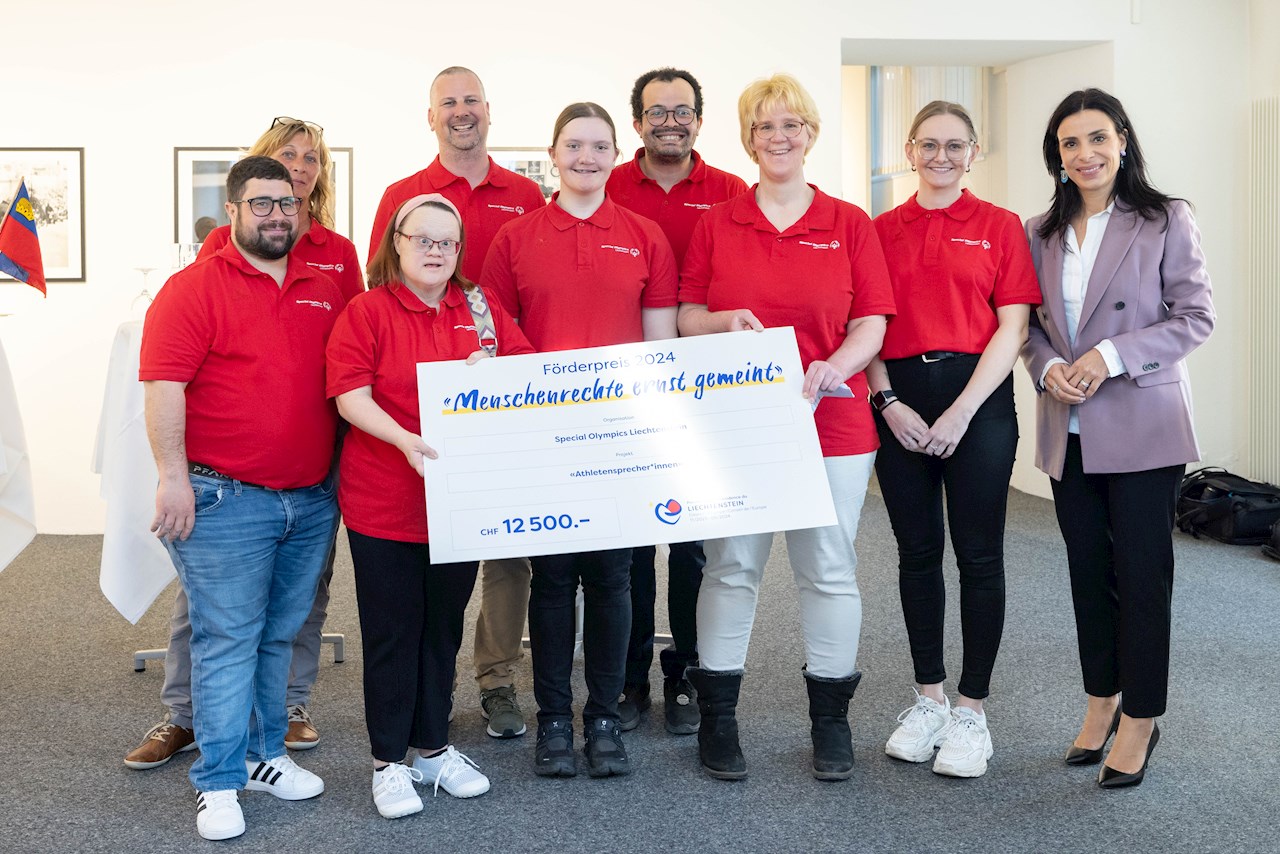 Regierungsrätin Dominique Hasler posiert mit dem Team des Projekts Athletensprecher/innen von Special Olympics Liechtenstein. Einige des Teams halten den Siegerscheck.