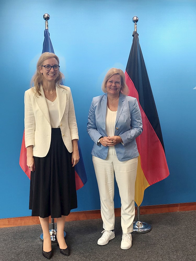 Die Innenministerinnen aus Liechtenstein und Deutschland, Sabine Monauni, links, und Nancy Faeser posieren für ein Foto vor blauem Hintergrund und den Fahnen ihrer Länder.