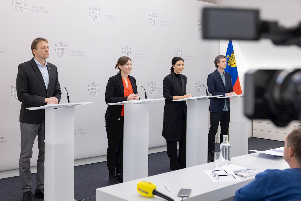Beat Wachter, Rachel Guerra, Dominique Hasler und Jürgen Tömördy stehen an Rednerpulten im Medienraum